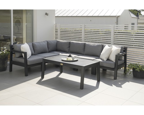 Trädgårdsmöbelset med hörnsoffa, kuddar och bord på en terrass