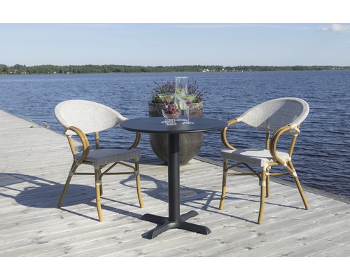 Rund trädgårdsbord med två rottingstolar på en träterrass vid sjön