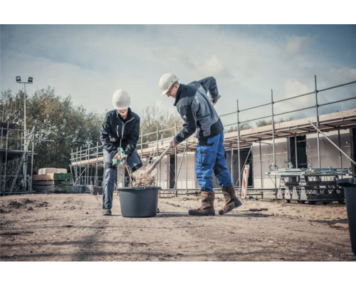 Två byggnadsarbetare arbetar med en spade och murbruksblandare på en byggarbetsplats.