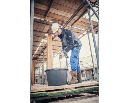 Hantverkare blandar murbruk med en elektrisk blandare på en byggnadsställning.