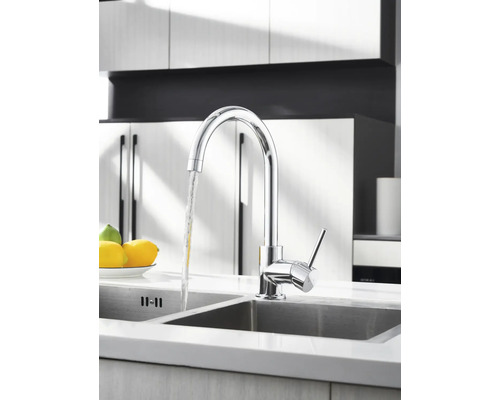 Krom köksblandare med rinnande vatten i en diskho