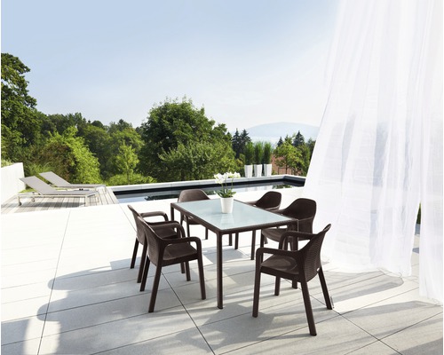 Trädgårdsscen med matbord och fyra stolar på en terrass