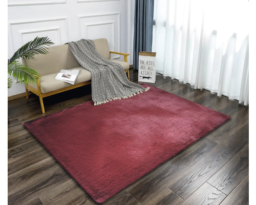 Vardagsrum med soffa och röd matta på trägolv