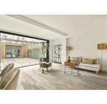 Ljust vardagsrum med altandörr, soffa och hyllor