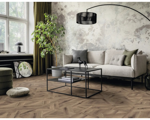 Vardagsrum med soffa, bord, krukväxt och trägolv i fiskbensmönster