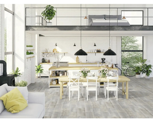 Ljust vardagsrum med kök, matplats, soffa och sovplats på ett loft.