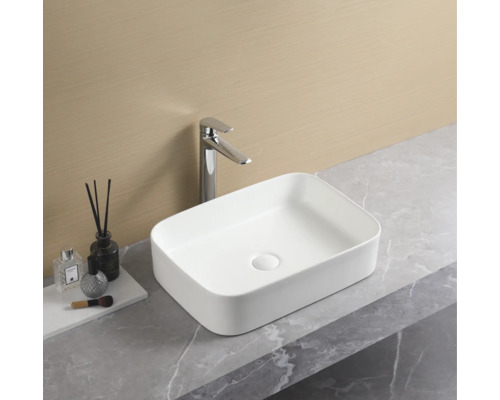 Rektangulärt tvättställ i keramik med blandare på en bänkskiva