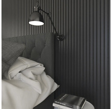 Sovrum med väggpaneler, säng, sänglampa och bok