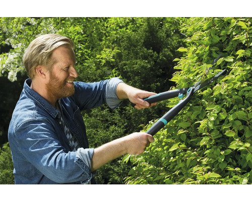 En man klipper en häck med en häcksax.