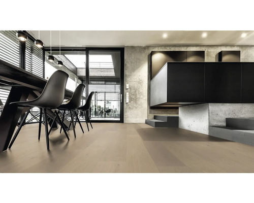 Ljust vardagsrum med trägolv, matbord och svarta stolar.