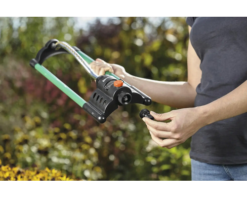 Kvinna monterar en gräsmattevattnare i trädgården