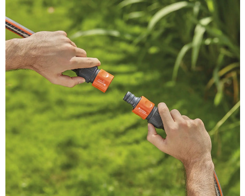 Två händer kopplar ihop en trädgårdsslangkoppling.