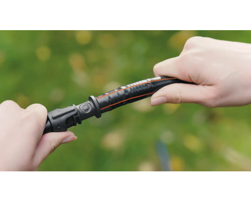 En person ansluter en trädgårdsslangdel till en trädgårdsslang.