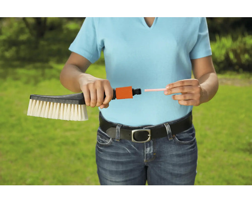 En kvinna ansluter en tvättborste till en slanganslutning.