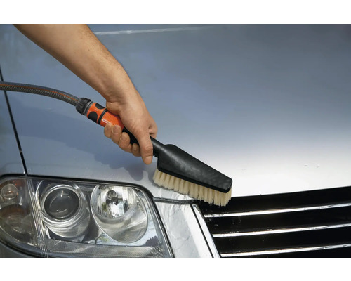 En person rengör en bil med en tvättborste.