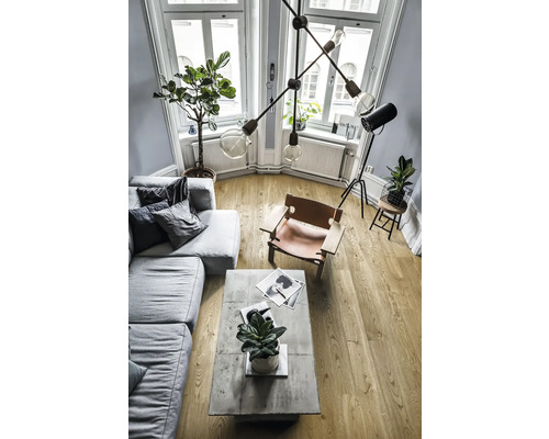 Vardagsrum med soffa, fåtölj, soffbord och krukväxter under en designlampa