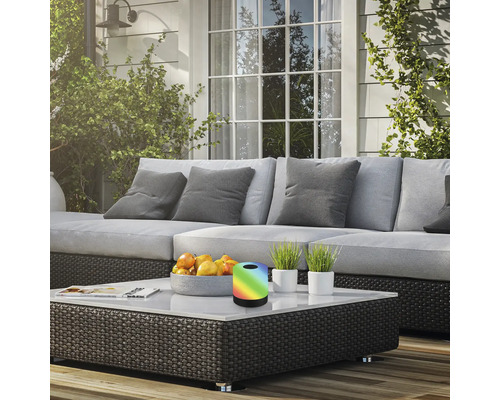 Terrassscen med soffa, soffbord, fruktskål, krukväxter och en bordslampa med färgskiftning.