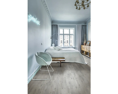 Sovrum med säng, stol, fönster och trägolv