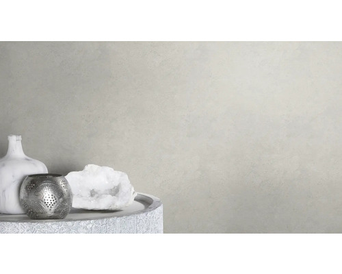 Dekorativ scen med vas, värmeljushållare och prydnadssten på ett bord framför en ljus vägg