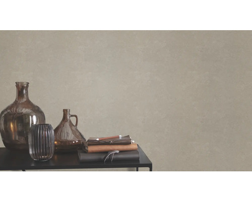 Dekorativa glasvaser och anteckningsböcker på ett bord framför en vägg med texturtapet