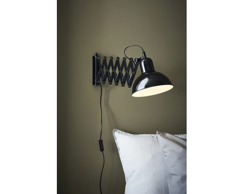 Vägglampa med saxarmsfäste ovanför en kudde