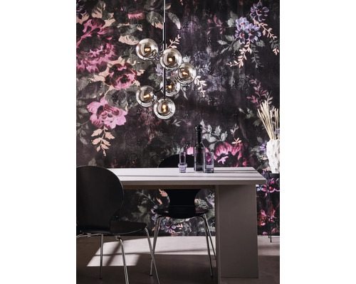 Matsal med matbord, stolar och en taklampa med flera glaskulor framför en blommig tapet.