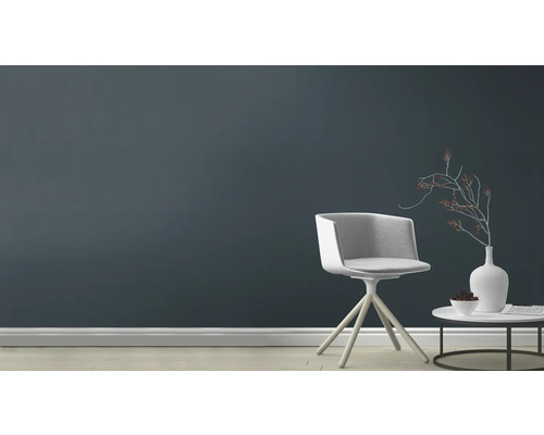 Vardagsrum med stol, bord och dekoration framför en mörk vägg.