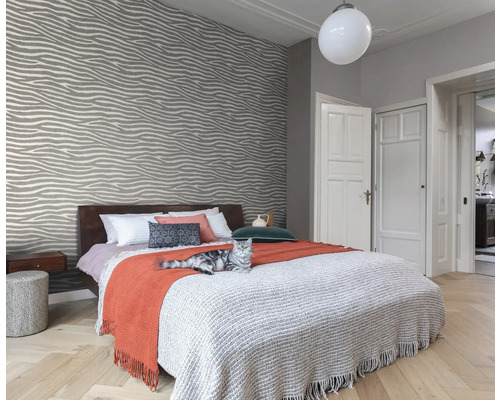 Modernt sovrum med mönstrad tapet, säng och katt