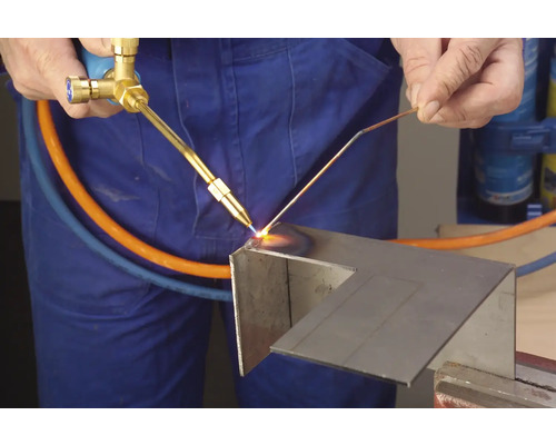 En hantverkare använder en lödlampa för att bearbeta metall.