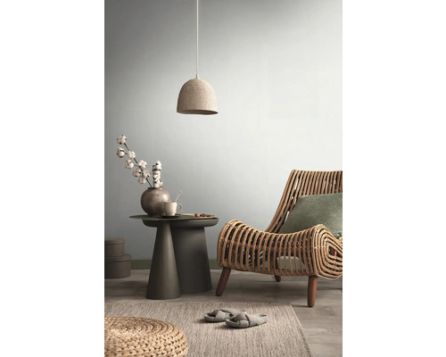 Vardagsrum med rottingfåtölj, sidobord och hänglampa för en ljus, mysig atmosfär