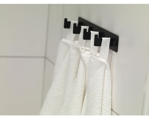 Handdukshängare med flera vita handdukar i badrummet