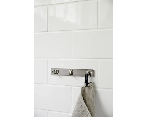 Handdukshängare med tre krokar och handduk på kakelvägg