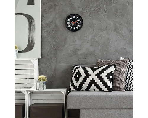 Vardagsrum med grå soffa, kuddar och väggklocka med synlig urverk