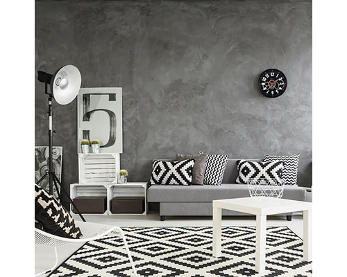 Vardagsrum med grå vägg, soffa med kuddar, matta med geometriskt mönster och vitt soffbord.