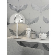 Närbild av ett rum med en lampa, vaser och mönstrad tapet.