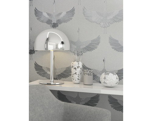 Närbild av ett rum med en lampa, vaser och mönstrad tapet.