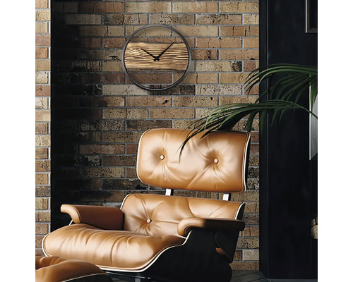 Vardagsrumsmiljö med en väggklocka med trädetaljer och en stoppad fåtölj framför en tegelvägg.