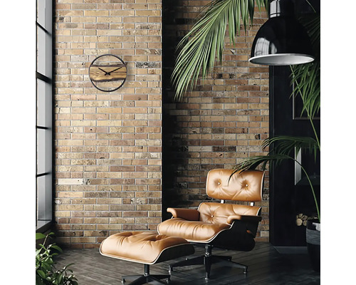 Vardagsrum med tegelvägg, fåtölj med fotpall, hänglampa och väggklocka i trä