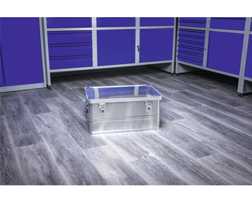 Verktygslåda i aluminium på ett verkstadsgolv framför blå verktygsskåp