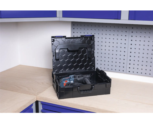 Öppen svart verktygslåda med borrmaskin på en arbetsbänk