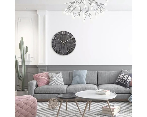 Vardagsrum med grå soffa, soffbord och väggklocka