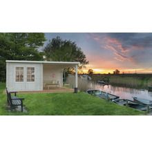 Trädgårdshus i trä med täckt uteplats vid vattnet med båtar