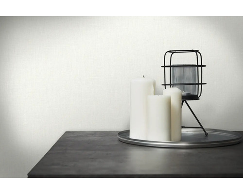 Dekorativ scen med vit textiltapet, ljus och en lykta