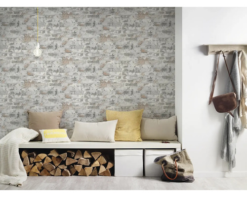 Vardagsrum med tapet med tegelmönster, sittbänk med kuddar, vedträn och dekoration