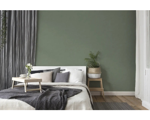 Sovrum med säng, sängbord och dekoration framför en grön vägg