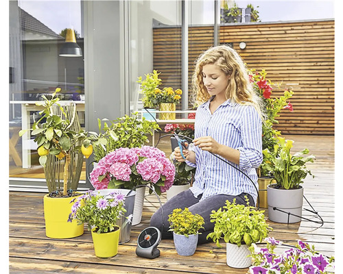 Kvinna skär bevattningsslang för växter på en terrass