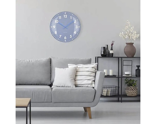 Vardagsrum med grå soffa, hylla och en rund väggklocka med urtavla