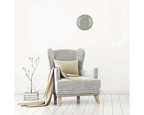 Vardagsrumsscen med fåtölj, kudde, filt, väggklocka och dekoration