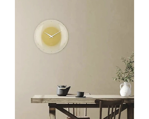 Väggklocka i vardagsrummet ovanför ett bord med tekanna och vas