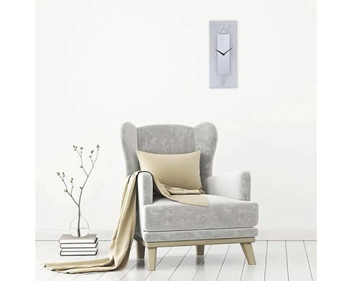 Vardagsrumsscen med fåtölj, kudde, filt och rektangulär väggklocka